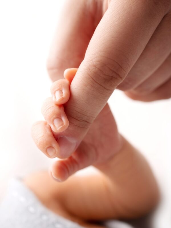 Close-up little hand of child and palm of mother and father. Close-up little hand of child and palm of mother and father. The newborn baby has a firm grip on the parent's finger after birth. A newborn holds on to mom's, dad's finger.